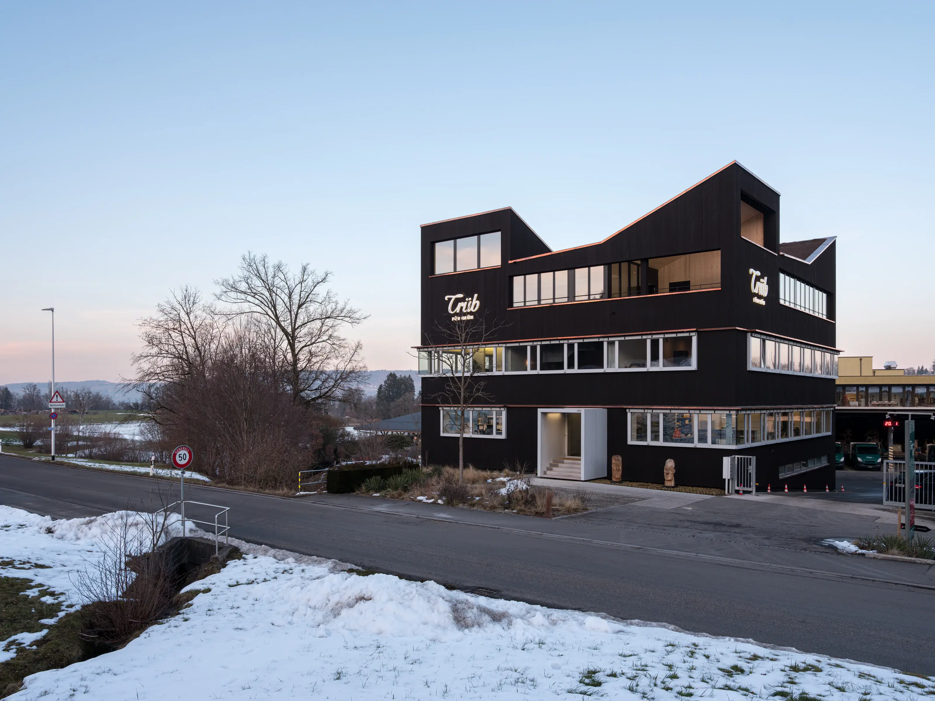 Aufstockung eines Bürogebäudes in Horgen mit dunkler Holzfassade in der Dämmerung.